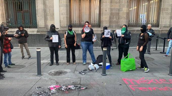 Feministas queman “cachito” de rifa del avión en Palacio Nacional