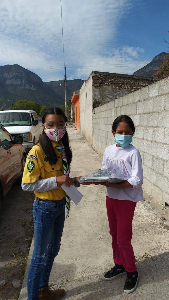 Niña scout ayuda a otros a tener una tableta o celular para que puedan tomar clases