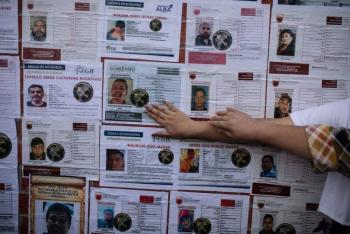 Familiares de desaparecidos pegan fichas de b&uacute;squeda durante marcha en CDMX